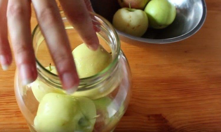 Naplňte sterilizovaná sklenice na vrchol důkladně umytými jablky.