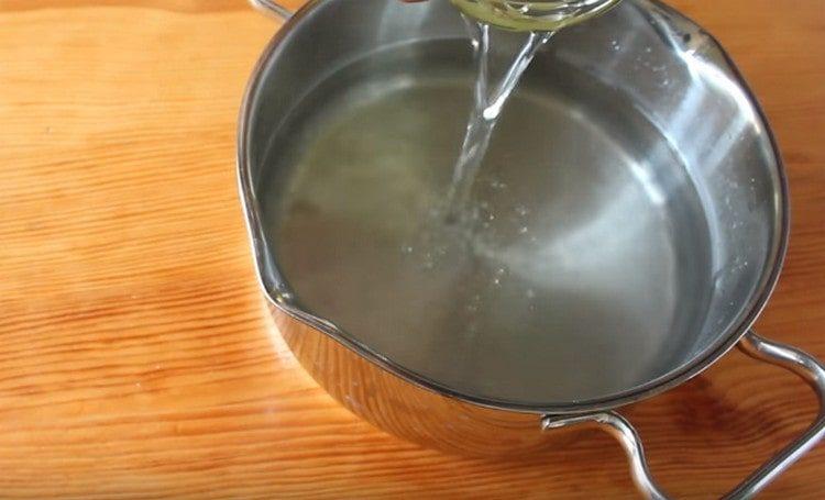 Gießen Sie Wasser aus einer Dose in eine Pfanne.