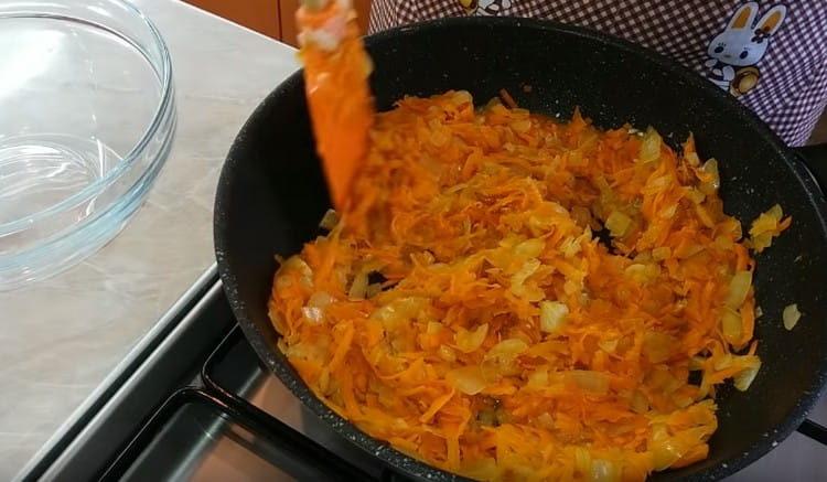 Fügen Sie die Karotten zu den Zwiebeln hinzu und geben Sie das Gemüse zusammen.