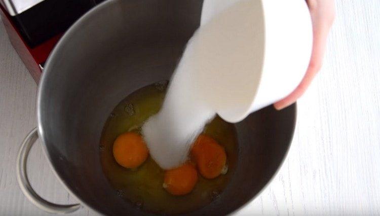 Maišytuvo dubenyje muškite kiaušinius ir įpilkite cukraus.