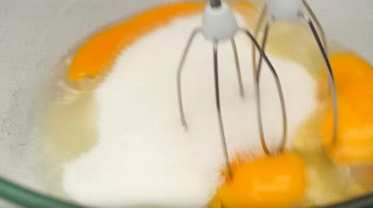 Разбийте яйцата със захарта с помощта на миксер.