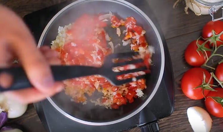 Gehackte Zwiebeln, Knoblauch und Tomaten in Öl anbraten.