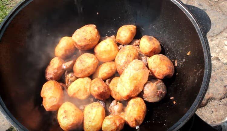 Ant mėsos išdėliokite anksčiau pakepintas bulves.