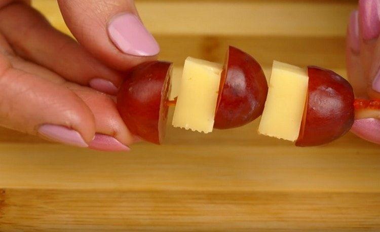 Metti alternativamente uno spiedino di uva e pezzi di formaggio.