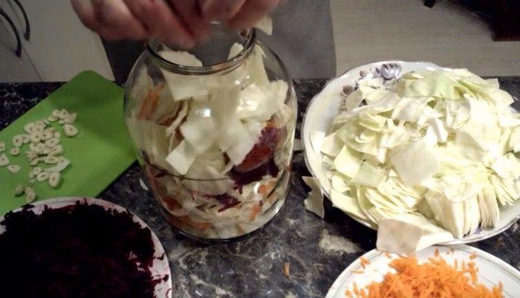 Mettiamo il cavolo, le carote, le barbabietole e l'aglio in un barattolo a strati.