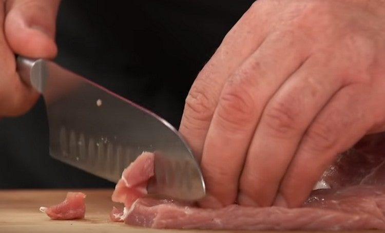 Нарежете свинското месо на малки парченца.