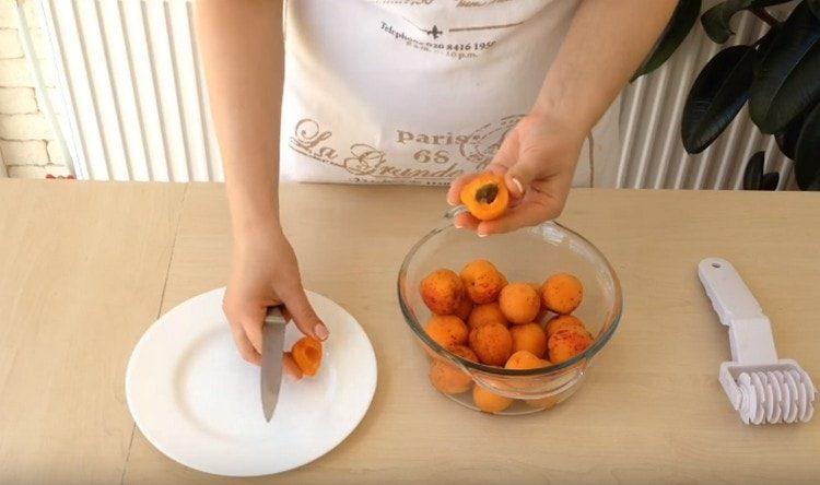 Die Aprikosen halbieren, die Kerne entfernen.