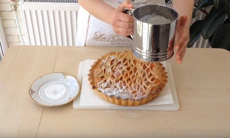 Pabarstykite gatavą abrikosų pyragą su cukraus pudra.