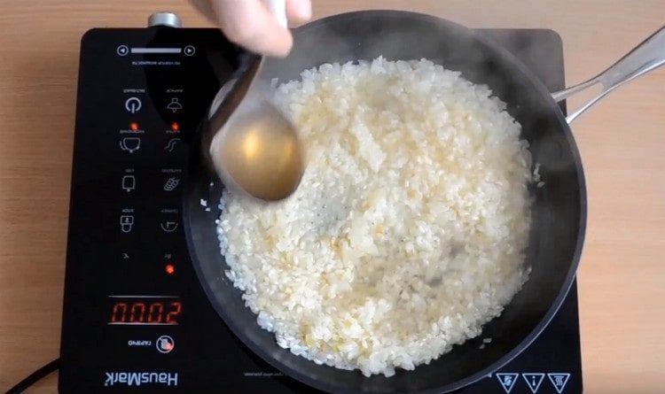 Eine Kelle wird zu der Reispilzbrühe gegeben.