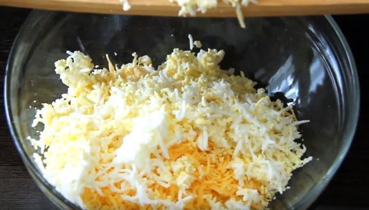 Reiben Sie das gekochte Ei auf einer Reibe und fügen Sie es dem Käse hinzu.