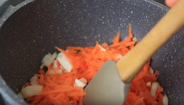 Friggere la cipolla con le carote in olio vegetale.