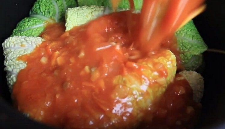 Kopūstų ritinius paskleiskite keptuvėje arba lėtoje viryklėje, supilkite kepti pomidorus.
