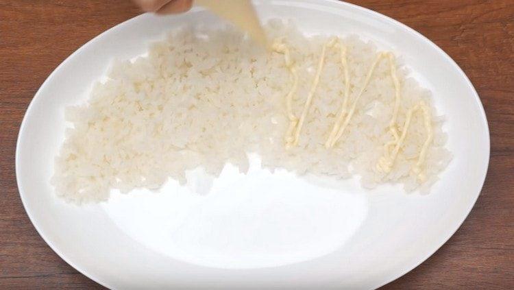 Reis mit der ersten Schicht Salat bestreichen, mit Mayonnaise einfetten.