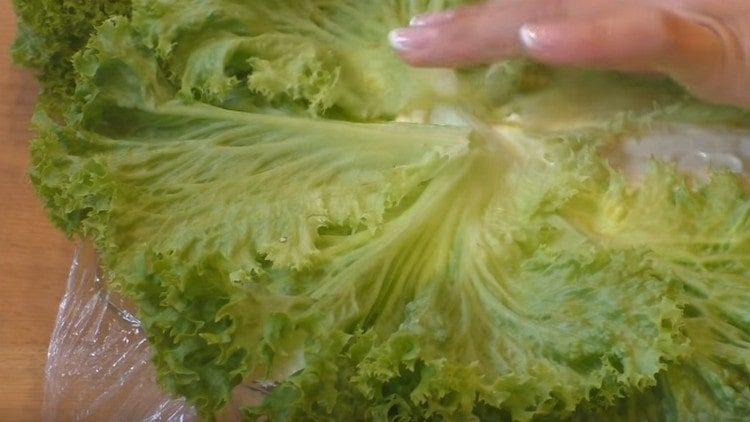 Αφαιρούμε το φιλμ προσκόλλησης από τη σαλάτα, καλύψτε το με φύλλα μαρουλιού.