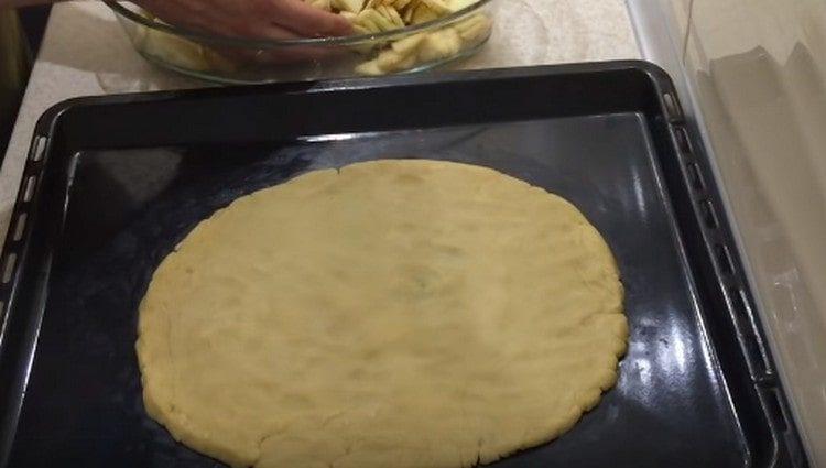Iš tešlos ant kepimo skardos formuojame apvalų pyrago pagrindą.