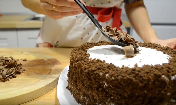 Die Ränder des Kuchens mit Krümeln aus dem Keks bestreuen, die Mitte mit Schokoladenstückchen dekorieren.