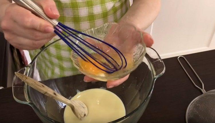 Gießen Sie Kondensmilch in eine Schüssel für Teig, fügen Sie ein geschlagenes Ei hinzu.
