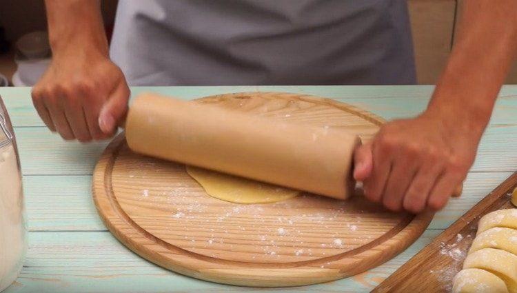 Wir rollen jede Teigportion mit einem Nudelholz zu einem Kuchen aus.
