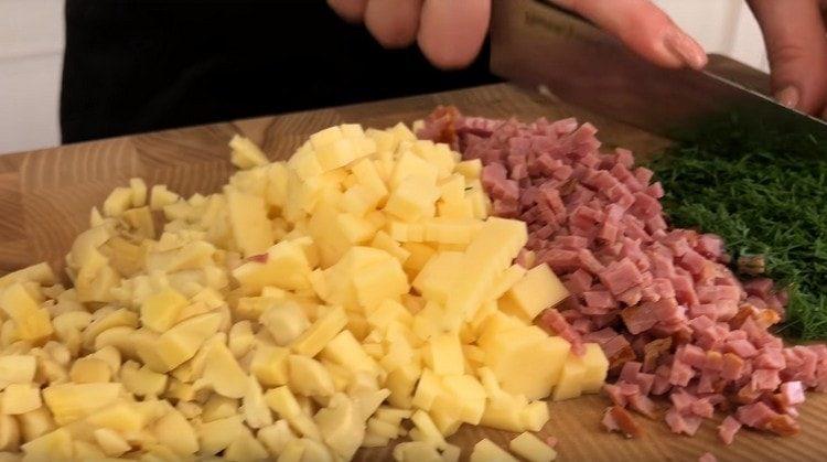 Ситно нарязваме консервираните гъби, наденицата, сиренето.