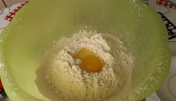 Į miltus įmušame kiaušinį ir supilame augalinį aliejų.