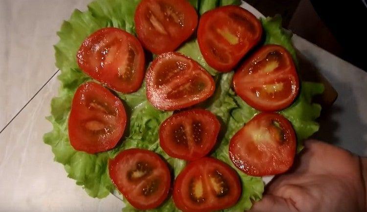 Pomidorus supjaustome apskritimais ir paskleidžiame ant salotų lapų.