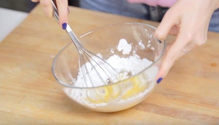 Kiaušinį sumaišykite su cukraus pudra ir vaniliniu cukrumi.