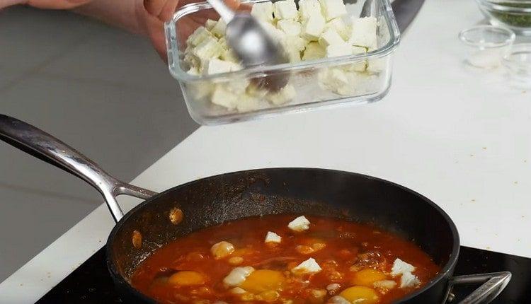Разбиваме яйцата в доматената маса и добавяме сиренето фета.