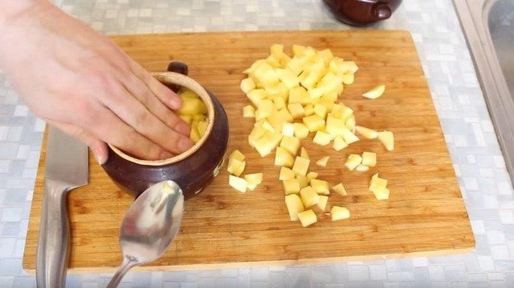 Die Kartoffeln in Würfel schneiden und in Töpfe auf das Fleisch legen.