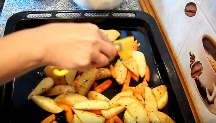 Разстиламе картофи с моркови върху тава, намазана с растително масло.