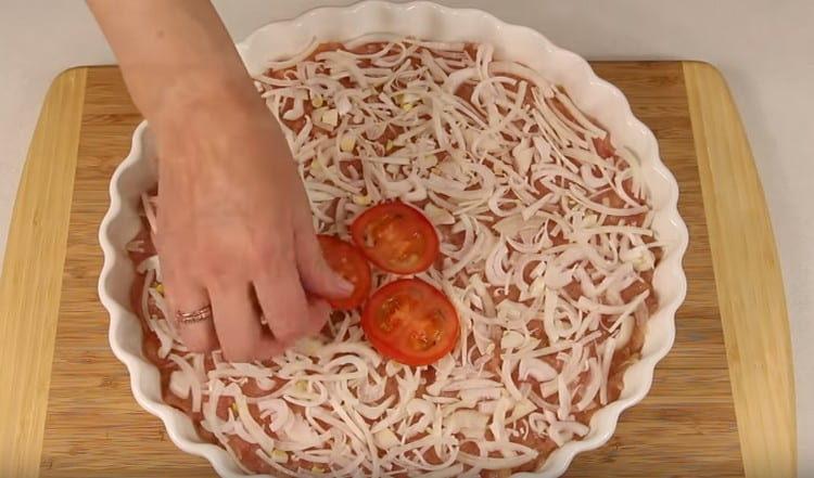 Ant maltos mėsos paskleiskite svogūną ir pomidorus.