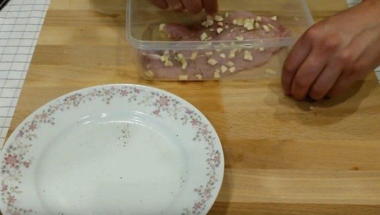 Osztja el a pulykahúst egy élelmiszer-tartályban, meghintjük fokhagymával