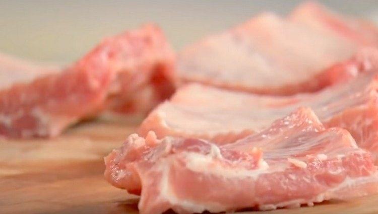 نغسل أضلاع لحم الخنزير ونقطعها إلى قسمين.
