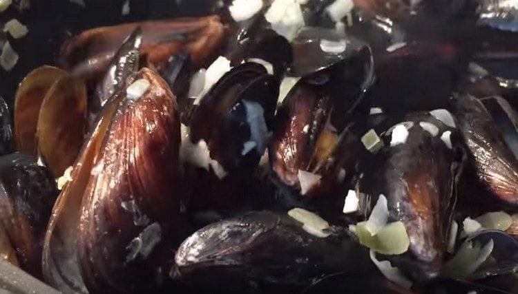Inilalagay namin ang mga mussel sa isang kawali sa sibuyas na may bawang.