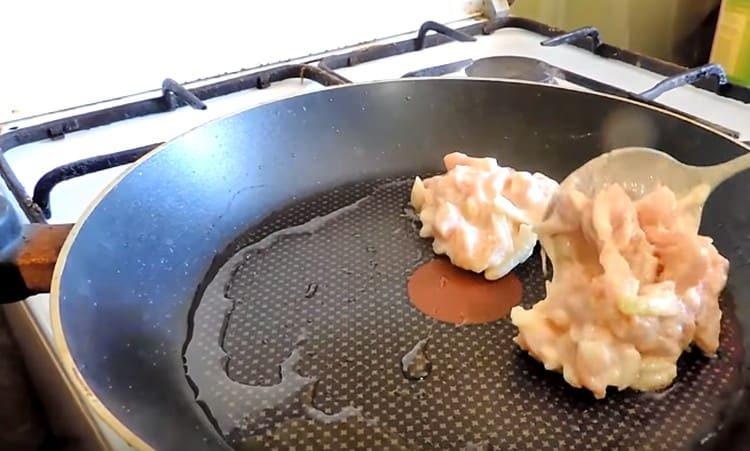 Geben Sie eine Fleischmischung mit einem Löffel in eine erhitzte Pfanne mit Pflanzenöl.