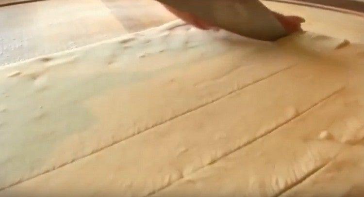 Lo strato di pasta viene tagliato in strisce strette.