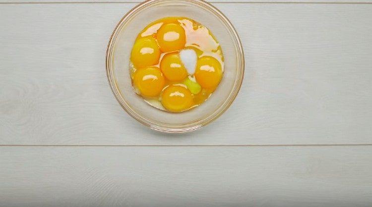 Σε ένα μπολ, βάλτε ένα αυγό και κρόκους αυγού, καθώς και αλάτι.